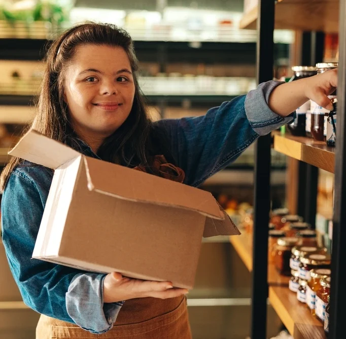disabled girl with down syndrome working as a shelve organiser