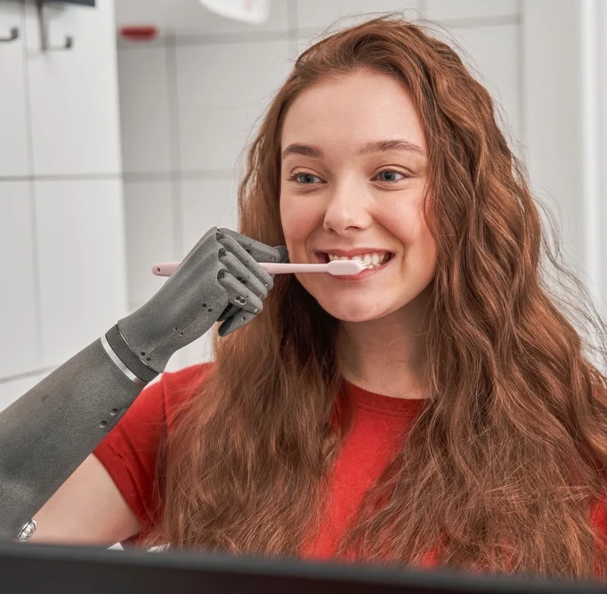 women with prosthetic arm brushing teeth
