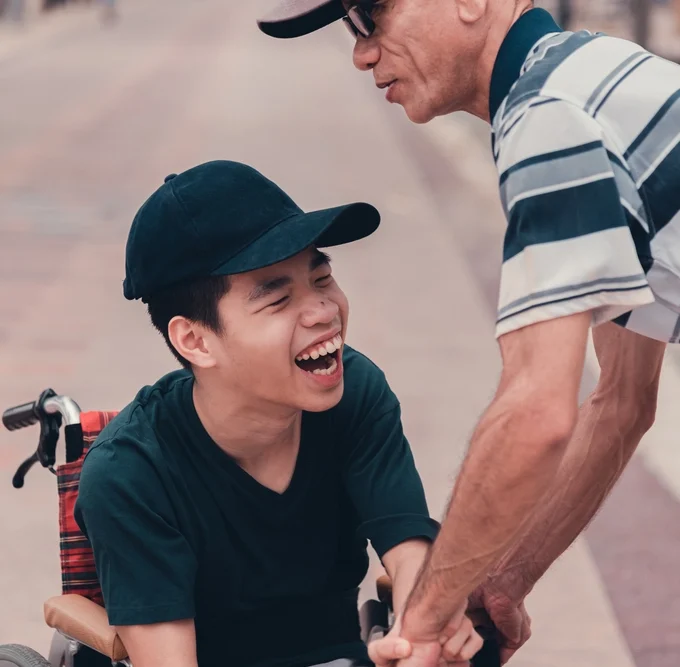 nurse helping a young boy with down syndrome disability on wheel chair smiling