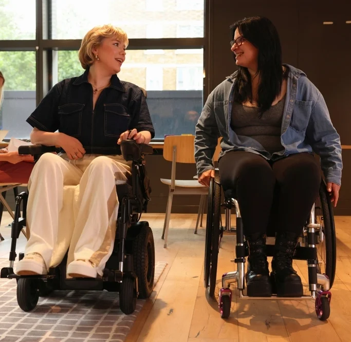 two women on wheel chairs laughing and chatting with each other