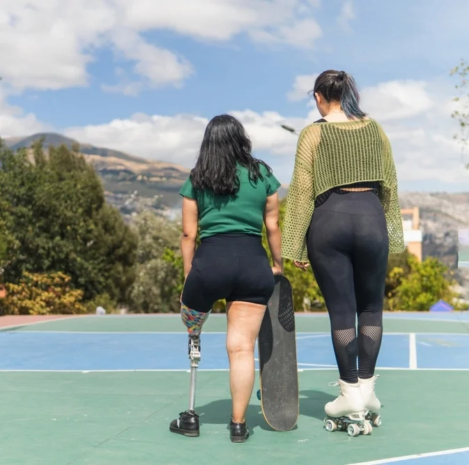 women with skates walking with a disabled women with prosthetic leg in tennis court
