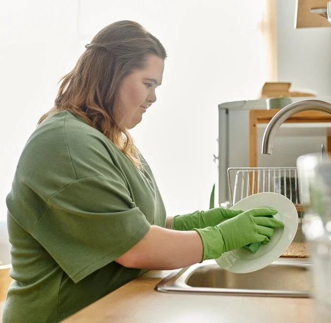 a young girl with down syndrome disability washing dishes